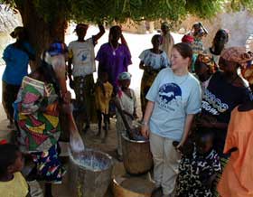 Volunteer Amanda Goetz bringing a moment of joy to some women in her village who are pounding millet in preparation for a wedding